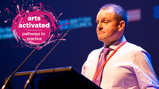 image of Pádraig Naughton from arts and disability ireland standing at a lectern. Arts Activated logo in the top left corner.