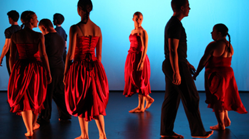 group of dancers on stage men and women in red dresses and black suits