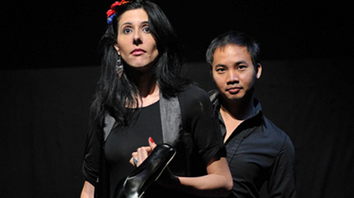 image of a man and a woman standing on dark stage looking toward the audience