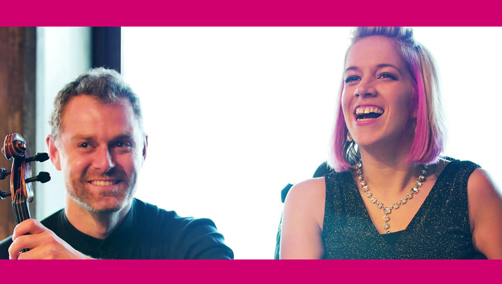 A member for the Australian Piano Quartet holds his string instrument and smiles next to Jessica Irwin who is laughing