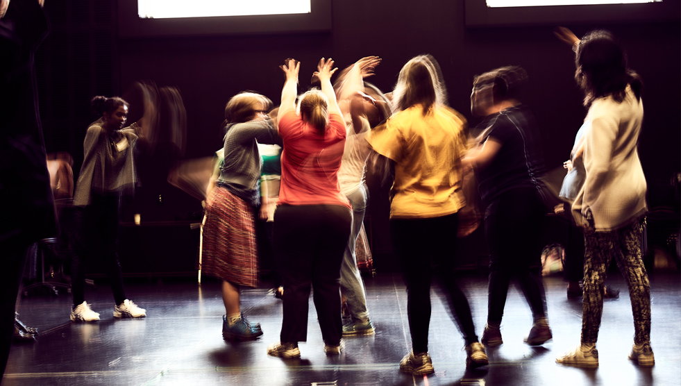 Group of theatre participants with their backs to the camera. The photo is blurry because the participants are moving. This photo is from the 2017 CAMP and was taken by Simon Fitzpatrick