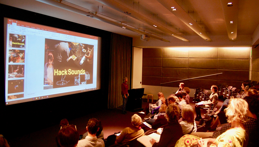 A recent ATAG meeting with a full audience to the right and HACK Sounds producer Liz Martin presenting with a large screen to the left